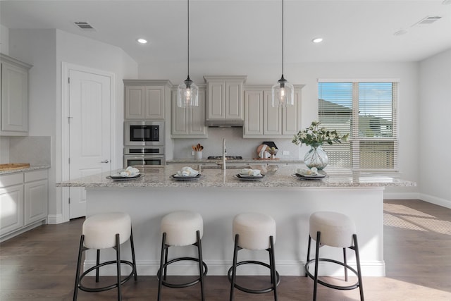 kitchen with dark wood-style flooring, visible vents, a kitchen breakfast bar, appliances with stainless steel finishes, and tasteful backsplash