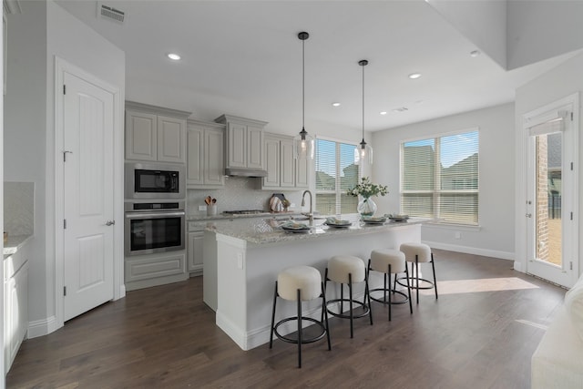 kitchen with visible vents, decorative backsplash, dark wood finished floors, appliances with stainless steel finishes, and a breakfast bar