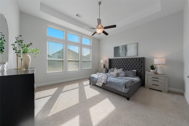 bedroom featuring baseboards, visible vents, a tray ceiling, and light colored carpet