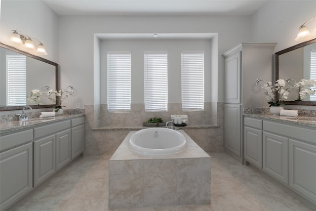 full bath with a garden tub, two vanities, a sink, and tile walls