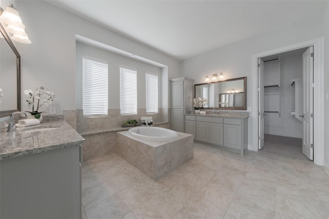 full bath featuring a bath, two vanities, and a sink