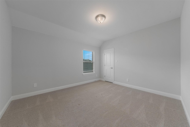 unfurnished room with light carpet, vaulted ceiling, and baseboards