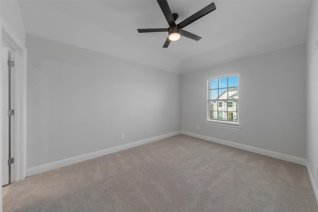 carpeted empty room featuring lofted ceiling, ceiling fan, and baseboards