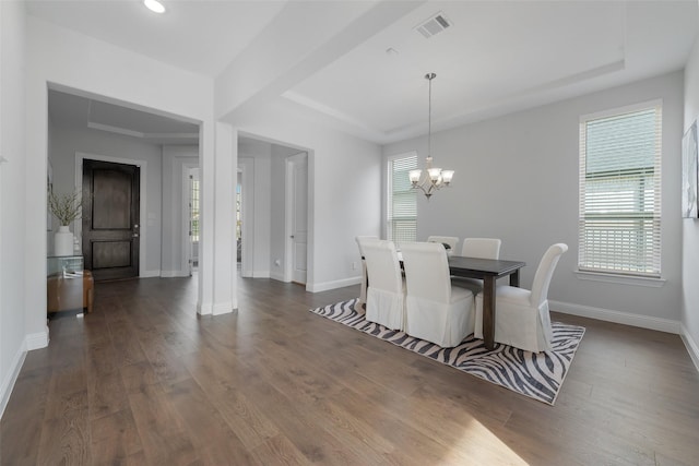 dining area featuring a raised ceiling, visible vents, an inviting chandelier, wood finished floors, and baseboards