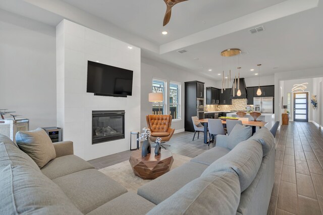 living room with baseboards, visible vents, light wood-type flooring, a fireplace, and recessed lighting