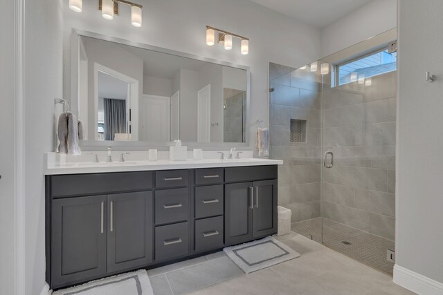 full bath with double vanity, a stall shower, tile patterned flooring, and a sink