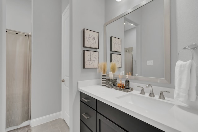 bathroom featuring curtained shower, vanity, baseboards, and tile patterned floors