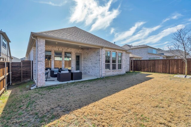 back of house featuring a shingled roof, a lawn, a patio, a fenced backyard, and brick siding