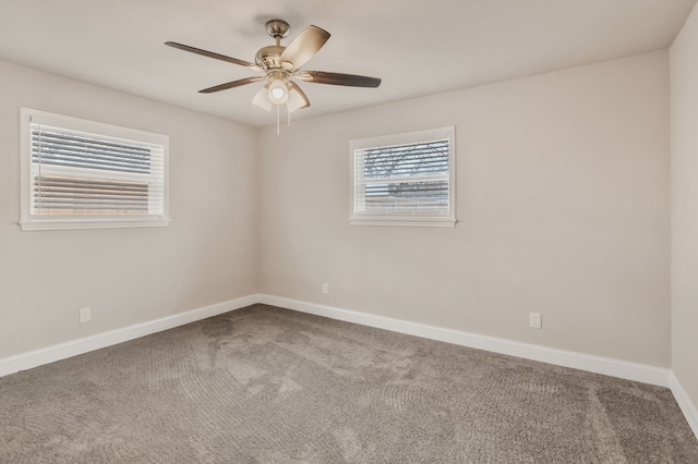 carpeted spare room featuring baseboards and a ceiling fan