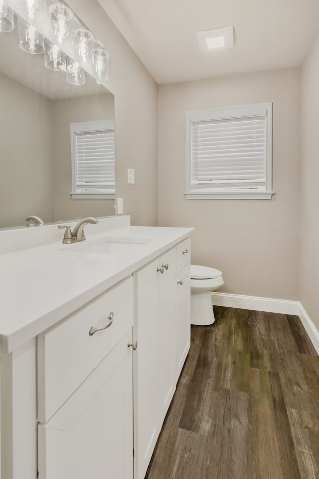 bathroom featuring toilet, vanity, baseboards, and wood finished floors