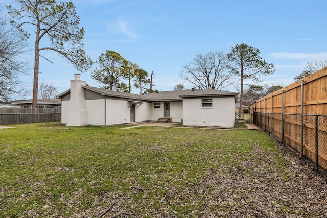 rear view of house featuring a yard, brick siding, and a fenced backyard