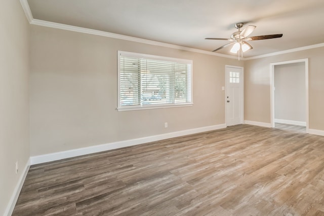 spare room with baseboards, crown molding, and wood finished floors