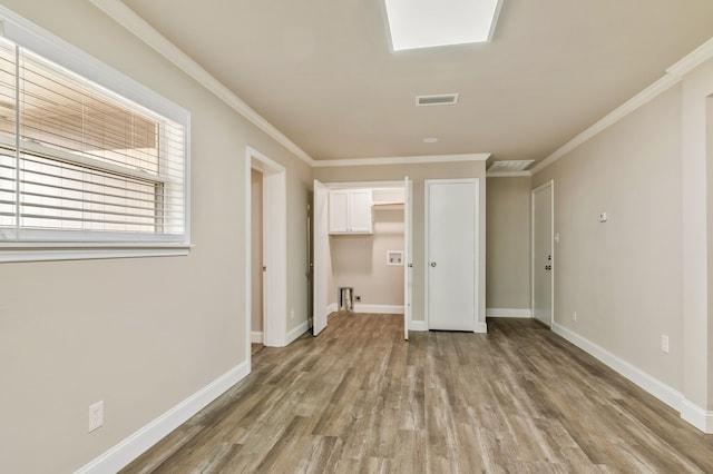 empty room with ornamental molding, visible vents, light wood-style flooring, and baseboards