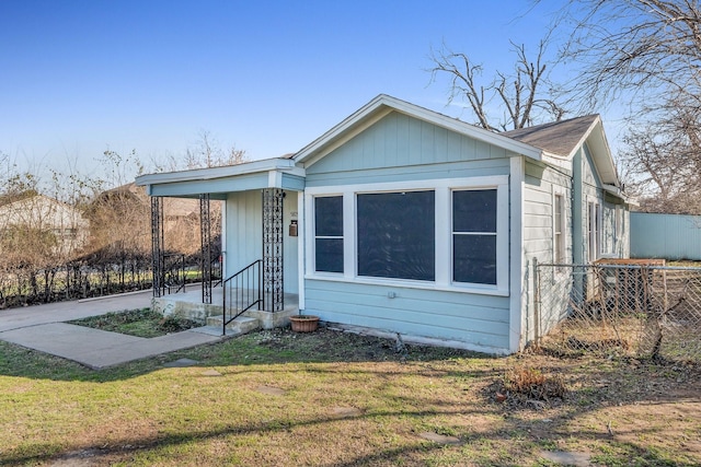 bungalow-style home featuring a front lawn and fence