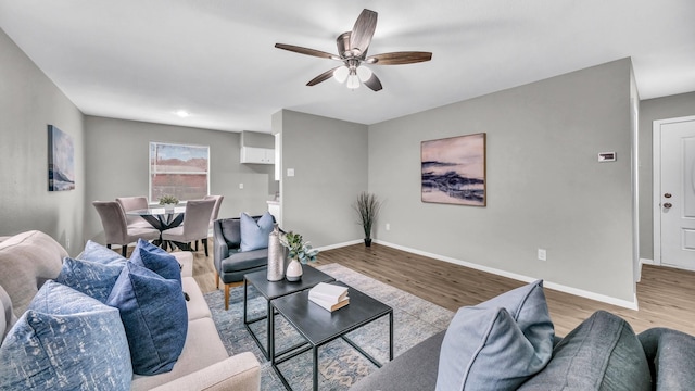 living area with light wood finished floors, baseboards, and a ceiling fan