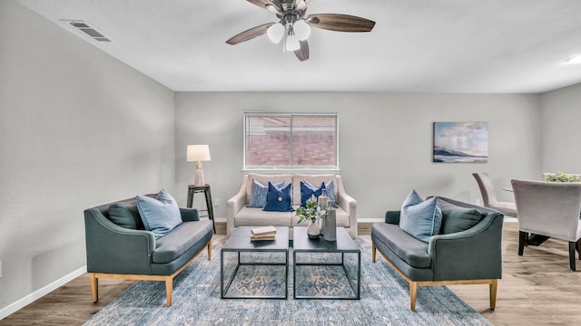 living area with baseboards, visible vents, ceiling fan, and wood finished floors