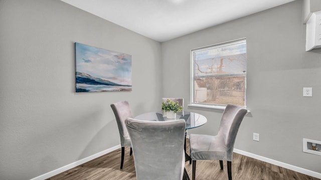 dining space with baseboards and wood finished floors