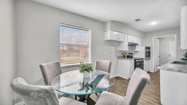 dining space with visible vents, light wood-style flooring, and baseboards