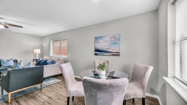 dining area featuring light wood-style flooring, baseboards, and a ceiling fan