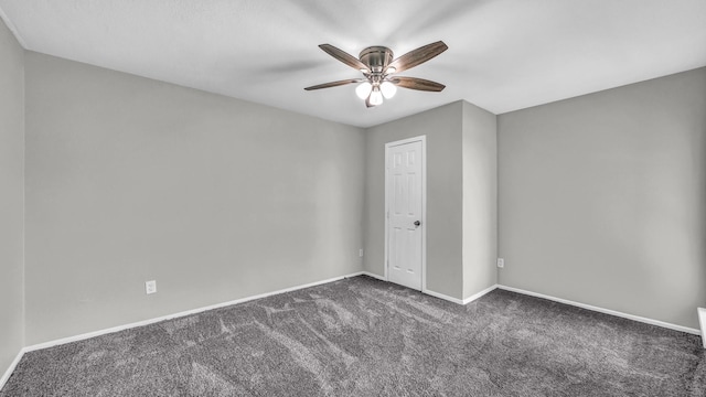 unfurnished bedroom with a ceiling fan, dark colored carpet, and baseboards