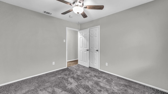 unfurnished bedroom featuring ceiling fan, visible vents, baseboards, a closet, and dark carpet