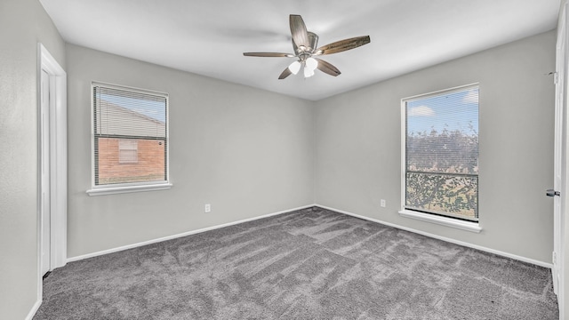 empty room featuring dark colored carpet, plenty of natural light, baseboards, and ceiling fan