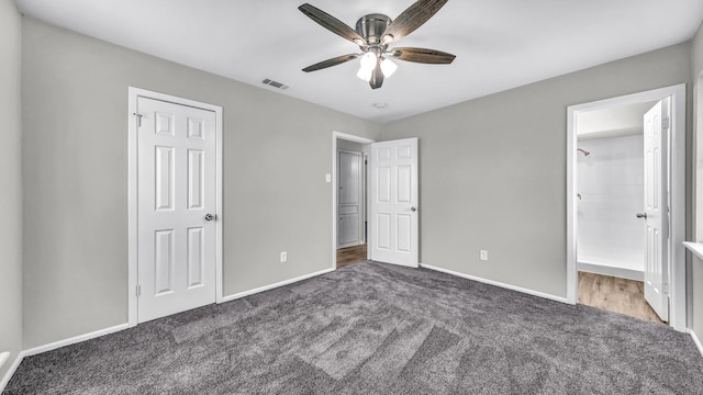 unfurnished bedroom with baseboards, visible vents, dark carpet, and ceiling fan