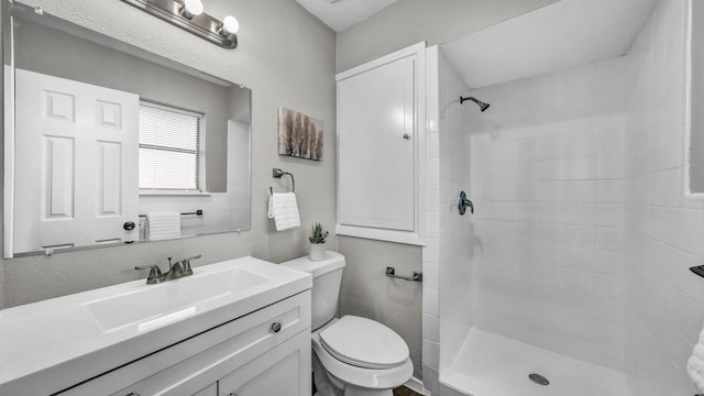 bathroom featuring a tile shower, vanity, and toilet