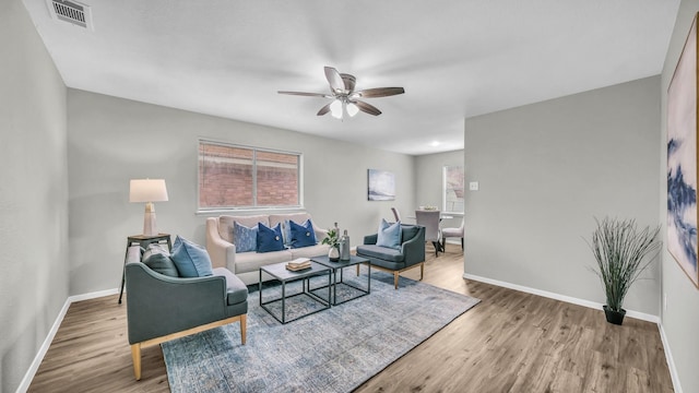 living room featuring ceiling fan, wood finished floors, visible vents, and baseboards