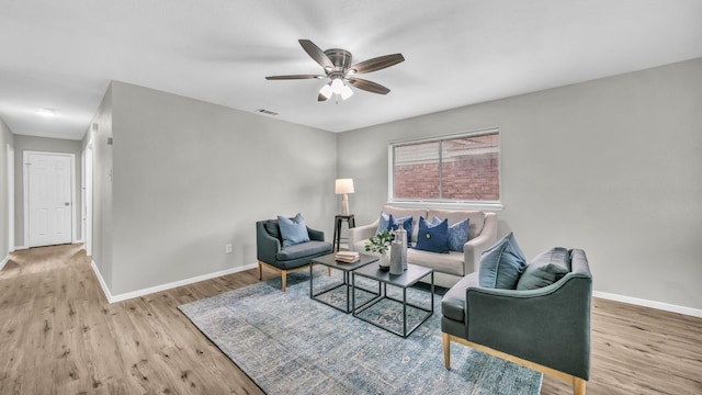 living area with light wood-style floors, visible vents, ceiling fan, and baseboards