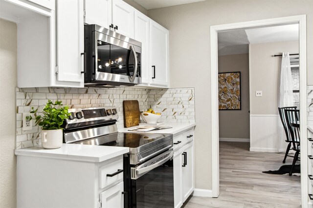 kitchen with stainless steel appliances, tasteful backsplash, light countertops, light wood-style flooring, and white cabinets