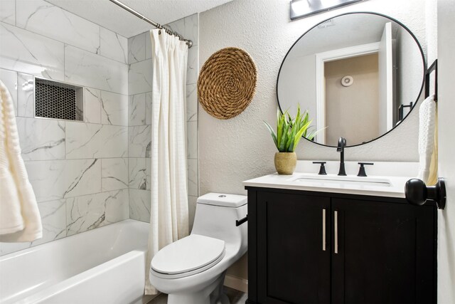 bathroom with a textured wall, shower / bath combo with shower curtain, vanity, and toilet