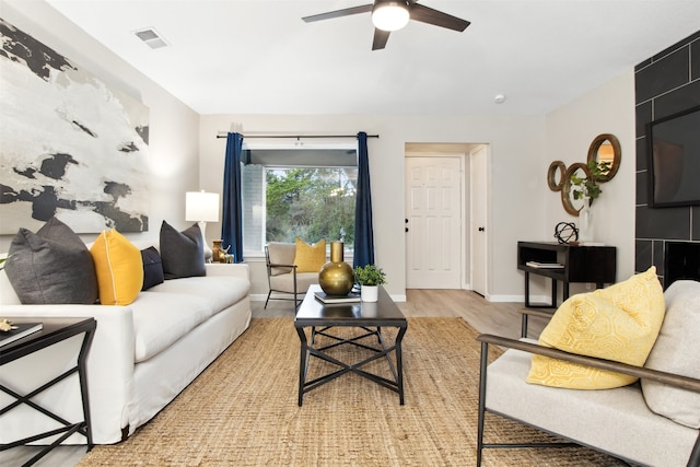 living area with light wood finished floors, baseboards, visible vents, and a ceiling fan