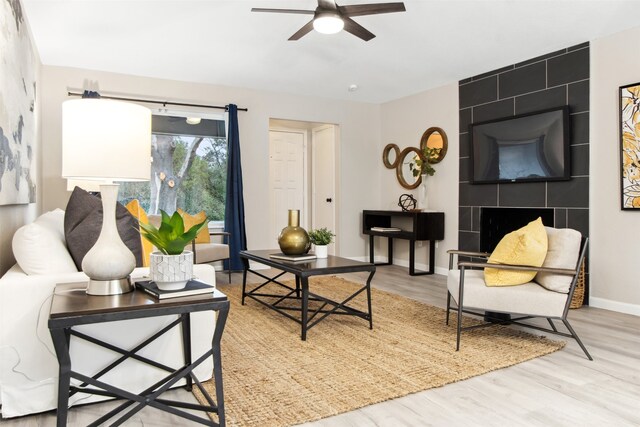 living room with a ceiling fan, baseboards, and wood finished floors