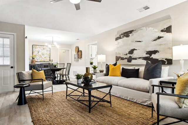 living area featuring ceiling fan, visible vents, and wood finished floors