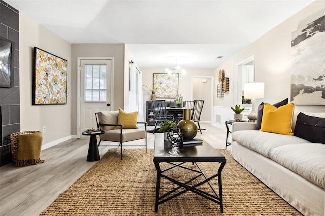 living room featuring baseboards, a fireplace, visible vents, and light wood-style floors