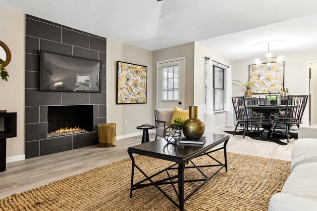 living area with a tile fireplace, baseboards, and wood finished floors