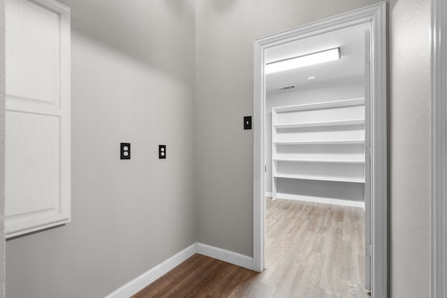 corridor with light wood-style flooring and baseboards