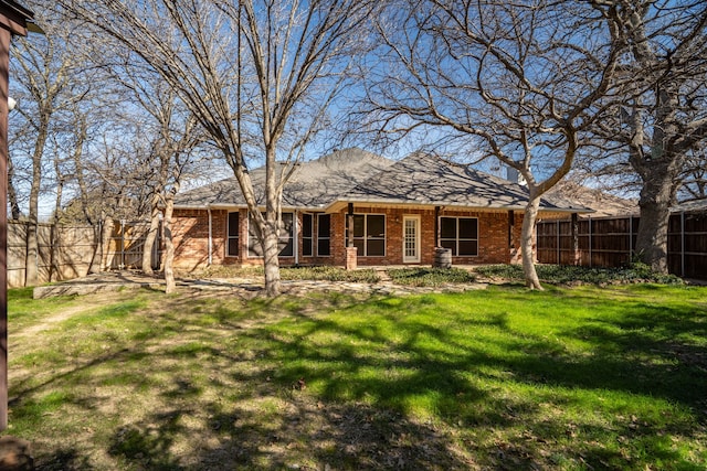 rear view of property with brick siding, fence, and a lawn