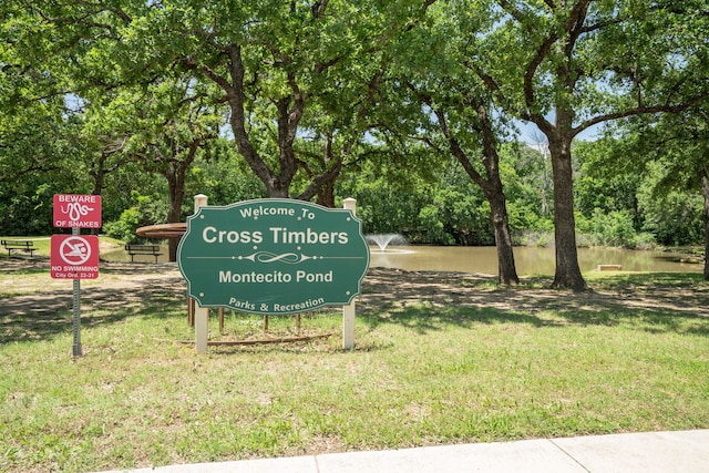 community sign with a water view and a lawn