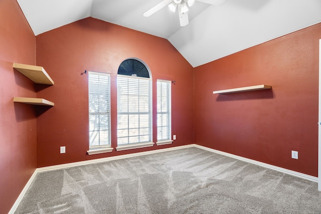 carpeted spare room with vaulted ceiling, baseboards, and ceiling fan