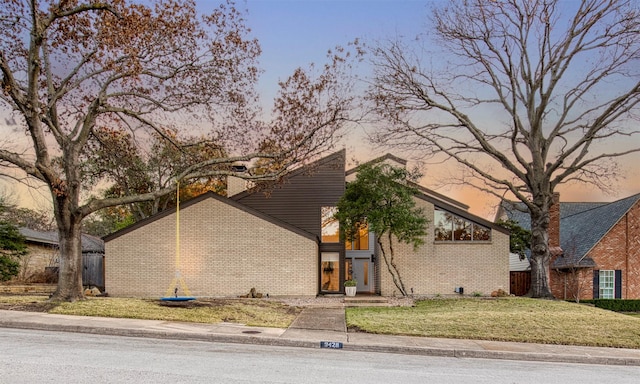 mid-century modern home featuring a front lawn and brick siding