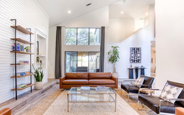 living room featuring light wood-style floors, visible vents, high vaulted ceiling, and baseboards