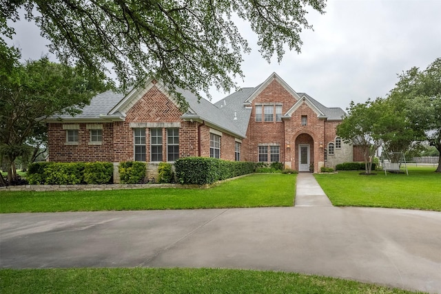 view of front of house with brick siding, a front lawn, and a shingled roof