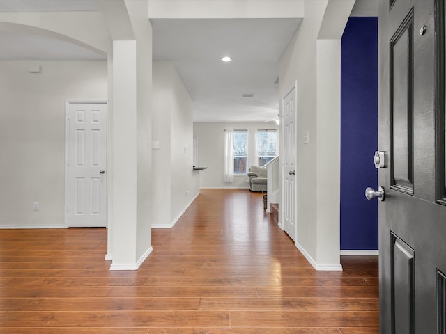 entrance foyer featuring arched walkways, wood finished floors, and baseboards