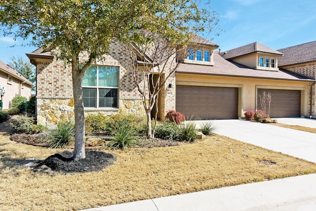 view of front of property with an attached garage, stone siding, concrete driveway, and stucco siding