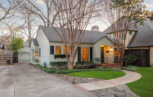 view of front of home featuring a chimney, roof with shingles, a gate, fence, and a front yard