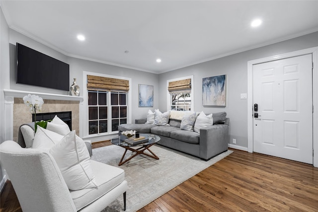 living room featuring recessed lighting, a fireplace, wood finished floors, baseboards, and crown molding