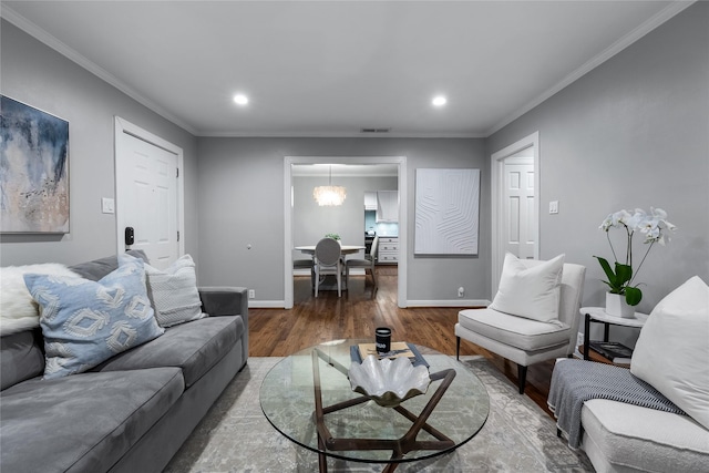 living area featuring visible vents, crown molding, baseboards, and wood finished floors