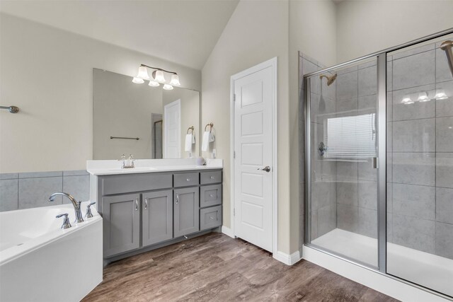 bathroom with lofted ceiling, wood finished floors, a garden tub, vanity, and a shower stall